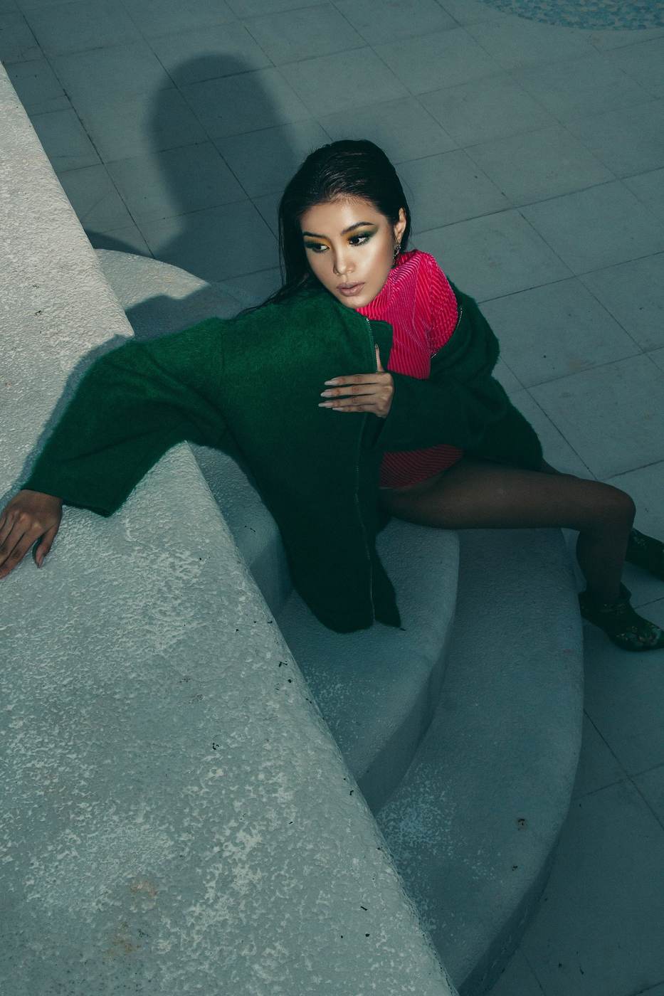 Demonstration photograph. A model in a green jacket photographed from above on pale concrete steps.