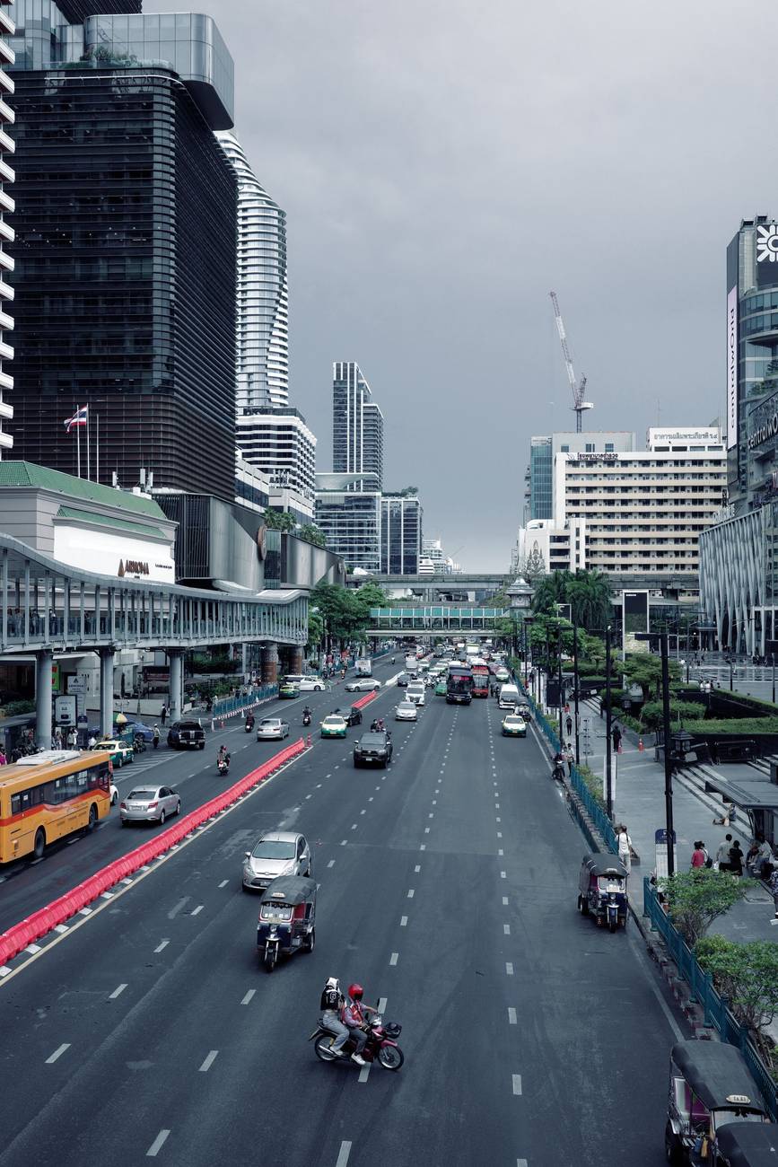 Demonstration photograph. A wide road seen from above under a flat grey sky, with tower blocks in the distance.