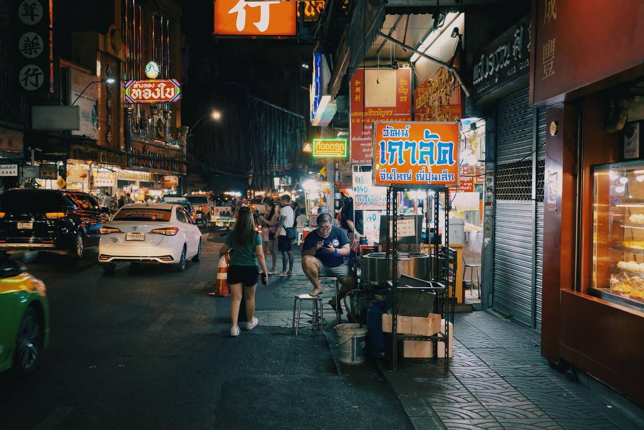 Demonstration photograph. A busy street at night lined with food carts and lit signs.